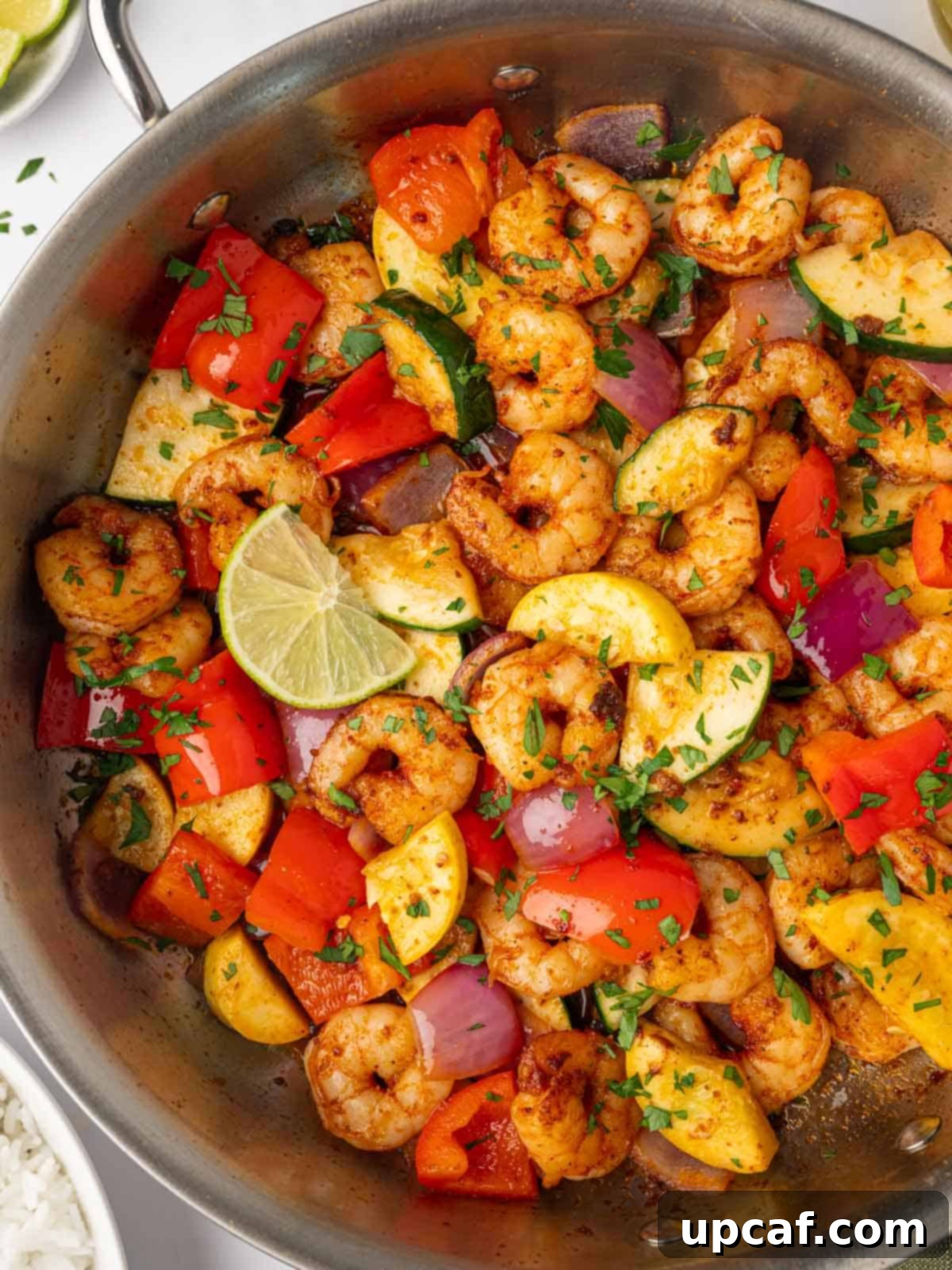 close-up of a skillet filled with sautéed shrimp and fresh vegetables.