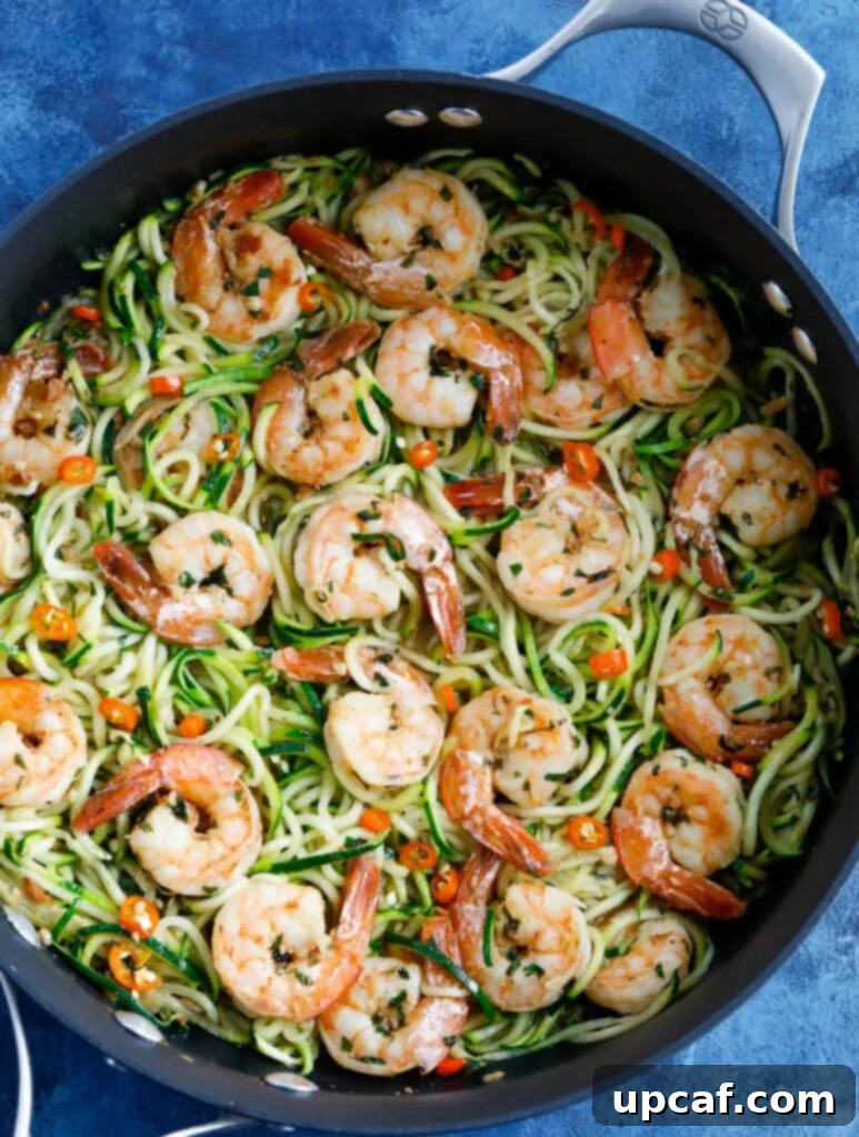 Garlic Shrimp Zoodles, a healthy pasta alternative Zucchini Noodles with Shrimp in a skillet, garnished with fresh herbs