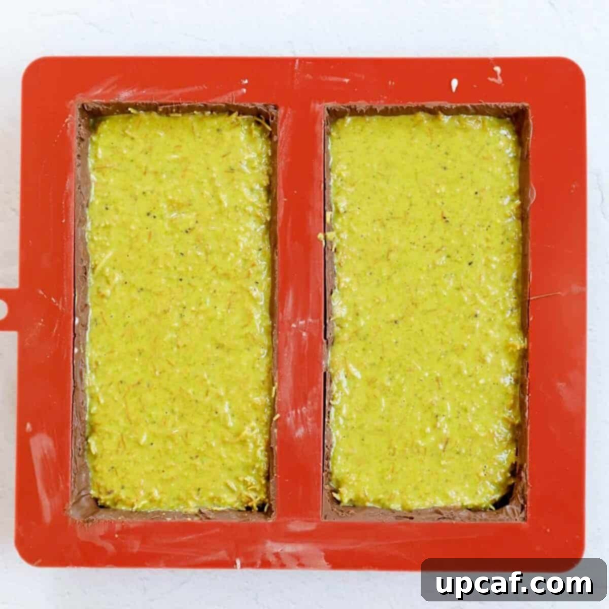 Process shot showing addition of pistachio cream kunafa into the chocolate mold.