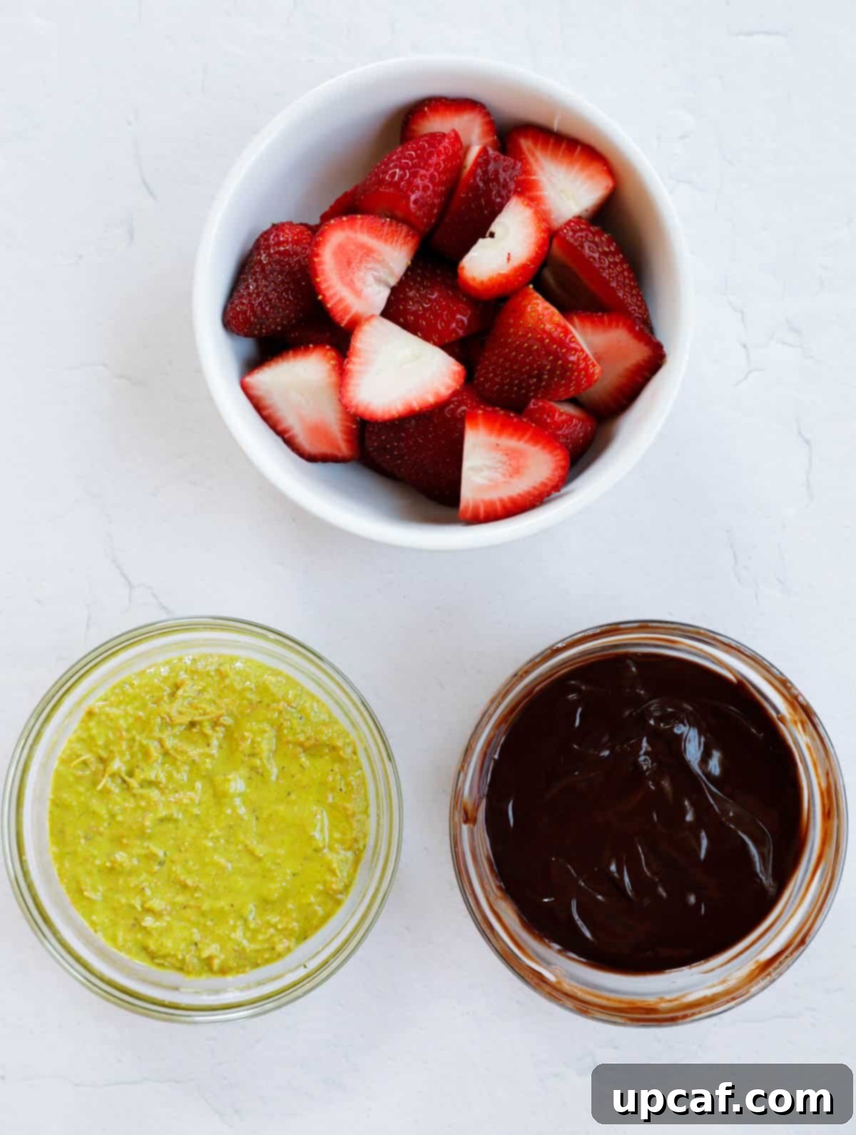 Laid out ingredients of Dubai Strawberry Cup including prepared kataifi mix, chocolate ganache, and sliced strawberries.