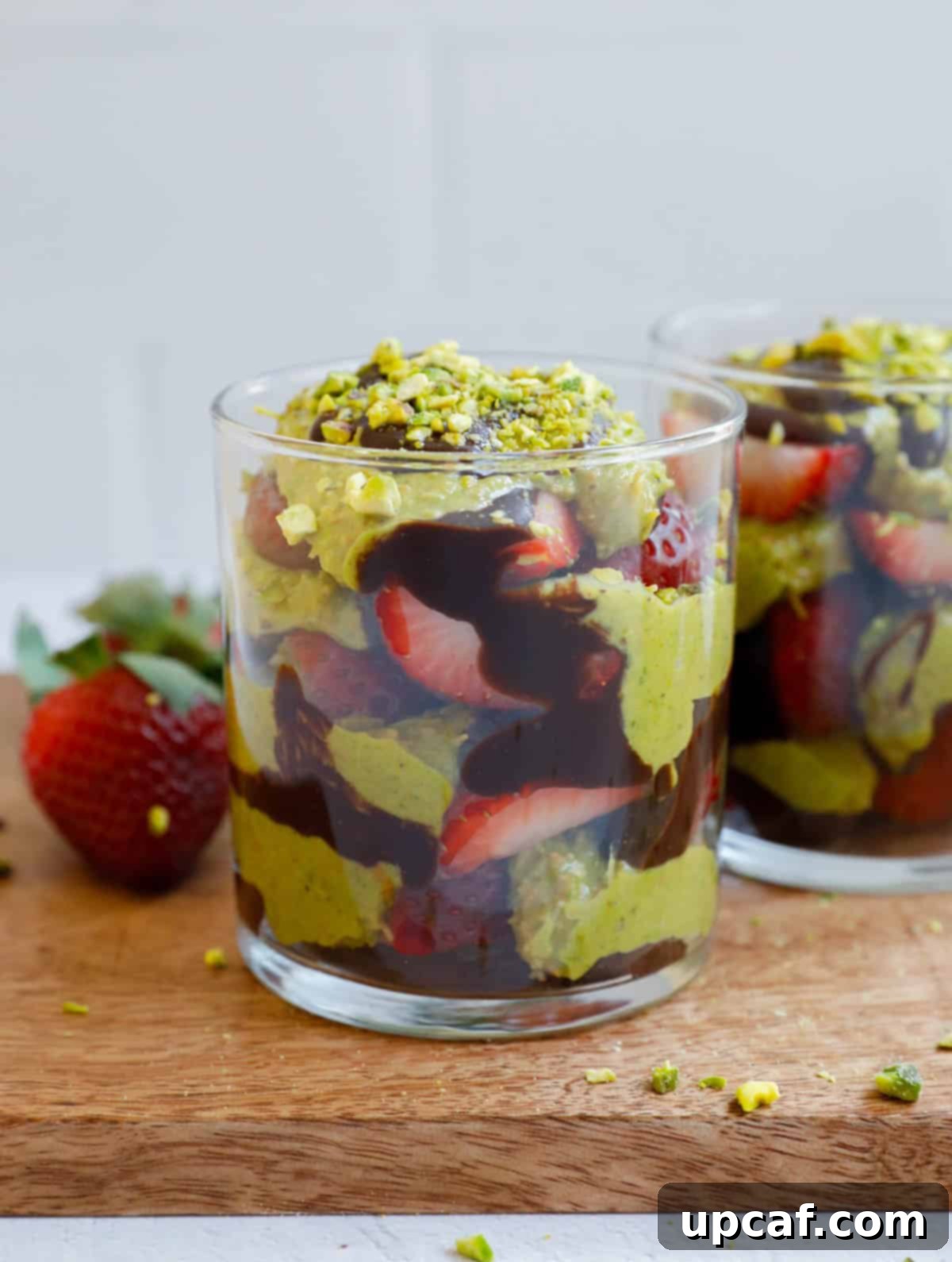 Two Dubai Strawberry Cups on a brown board, garnished with pistachios.