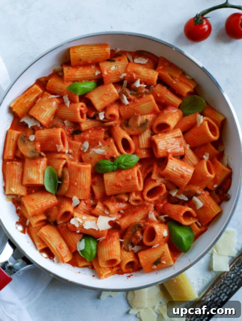 A vibrant bowl of Creamy Red Pepper Pasta, showcasing its rich, red sauce and perfectly coated rigatoni in a skillet