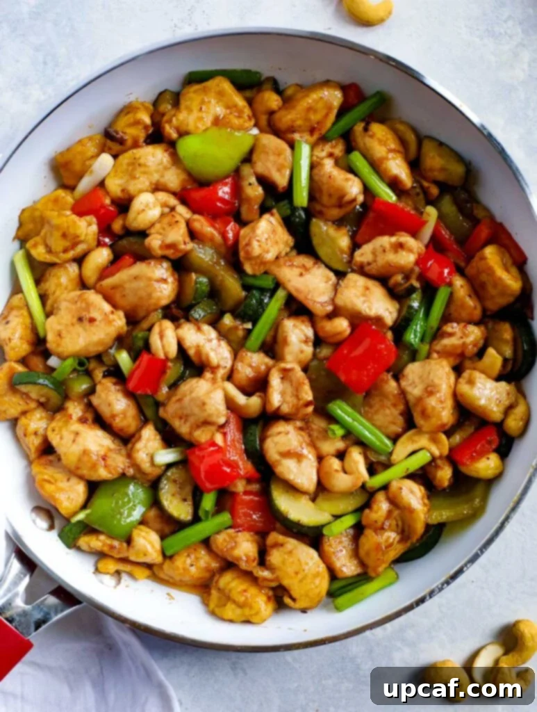 Homemade Spicy Cashew Chicken Stir Fry Spicy Cashew Chicken recipe in a skillet, showcasing golden chicken pieces, colorful bell peppers, and cashews glistening in a rich sauce.