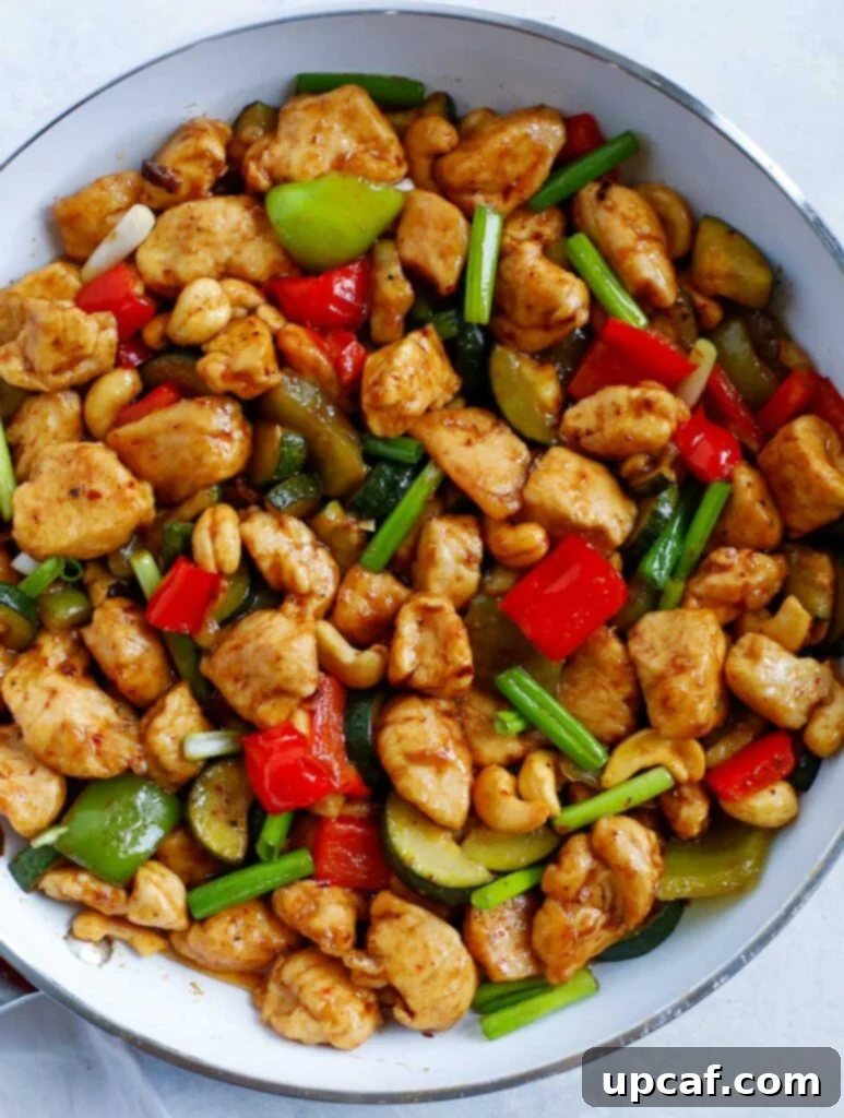 Delicious Chicken Cashew Stir Fry A top-down view of the completed Cashew Chicken stir-fry presented beautifully in a large skillet, garnished with fresh green onions.