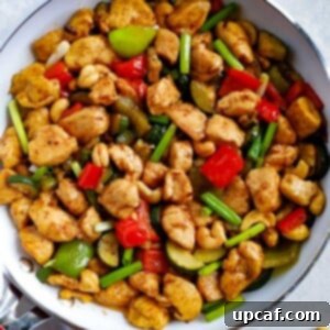 Fiery Cashew Chicken Delight 2 Delicious Spicy Cashew Chicken served in a bowl, garnished with green onions and cashews.