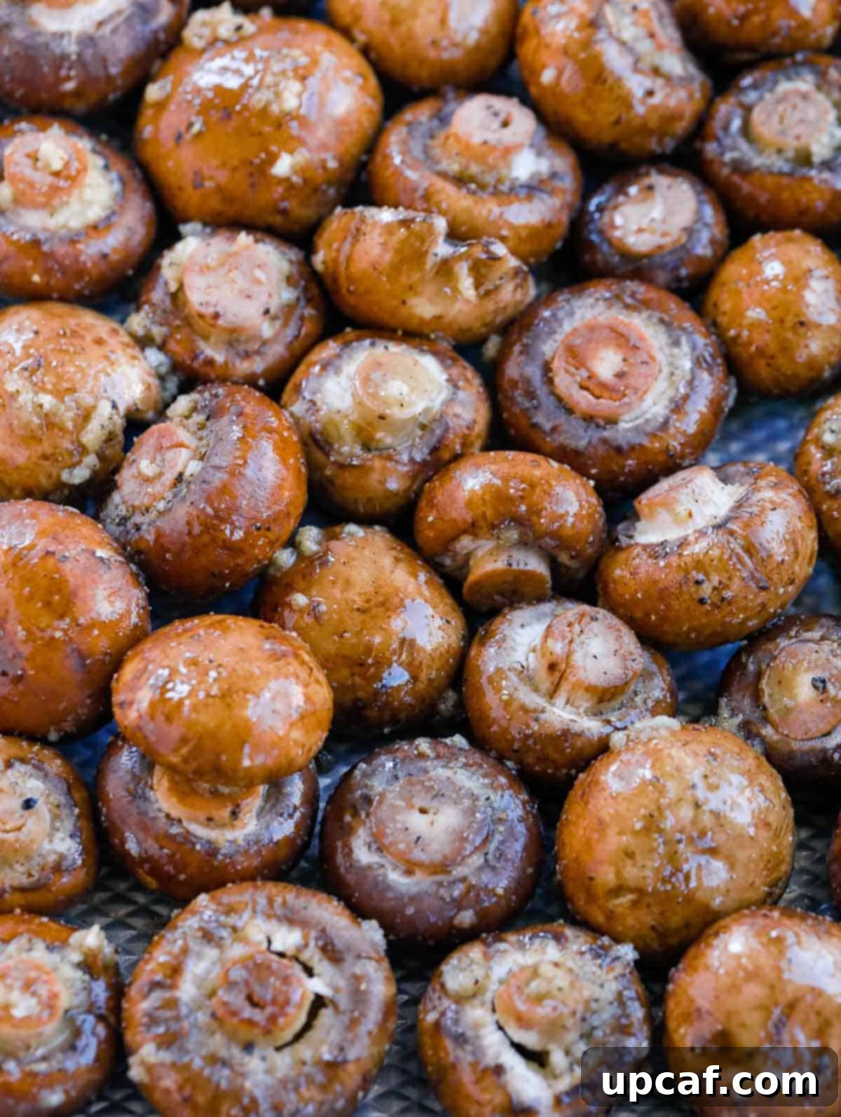 Mushrooms seasoned with garlic butter sauce, spread on a sheet pan before roasting.