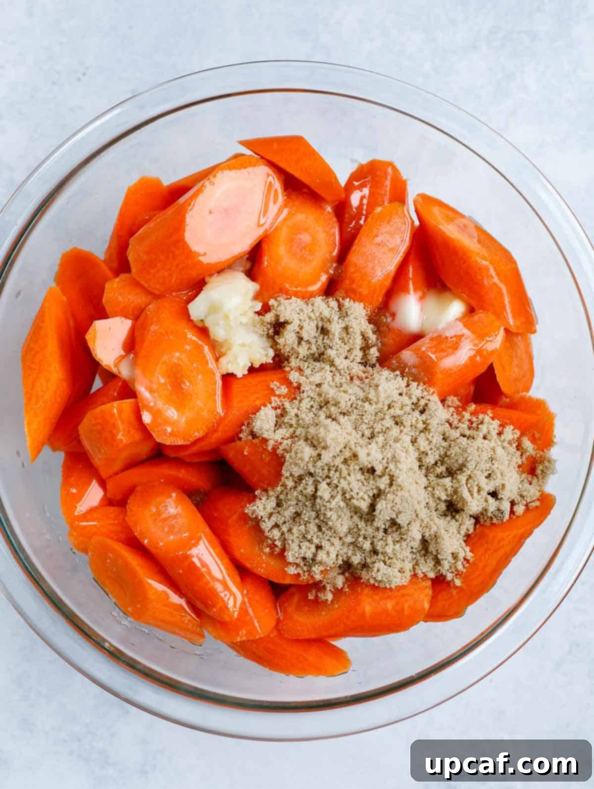 brown sugar glazed carrots in a clear bowl before mixing ingredients together.