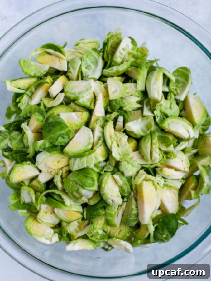 Shredded Brussels sprouts in a clear glass bowl, ready for mixing.