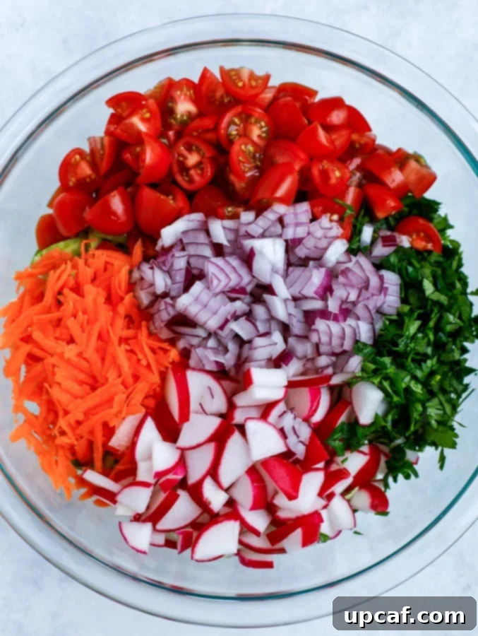 A vibrant mix of chopped vegetables, including Brussels sprouts, tomatoes, and carrots, in a bowl.