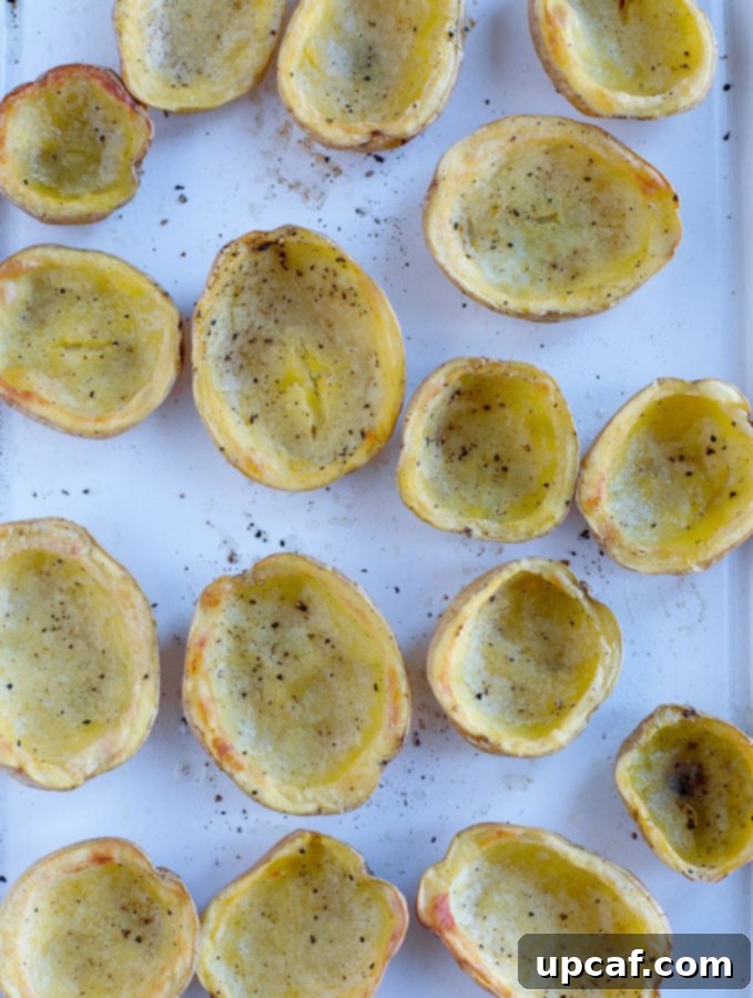 baked potatoes Baked potato skins arranged on a baking tray, showing their golden brown edges after the first bake, ready for the next step.