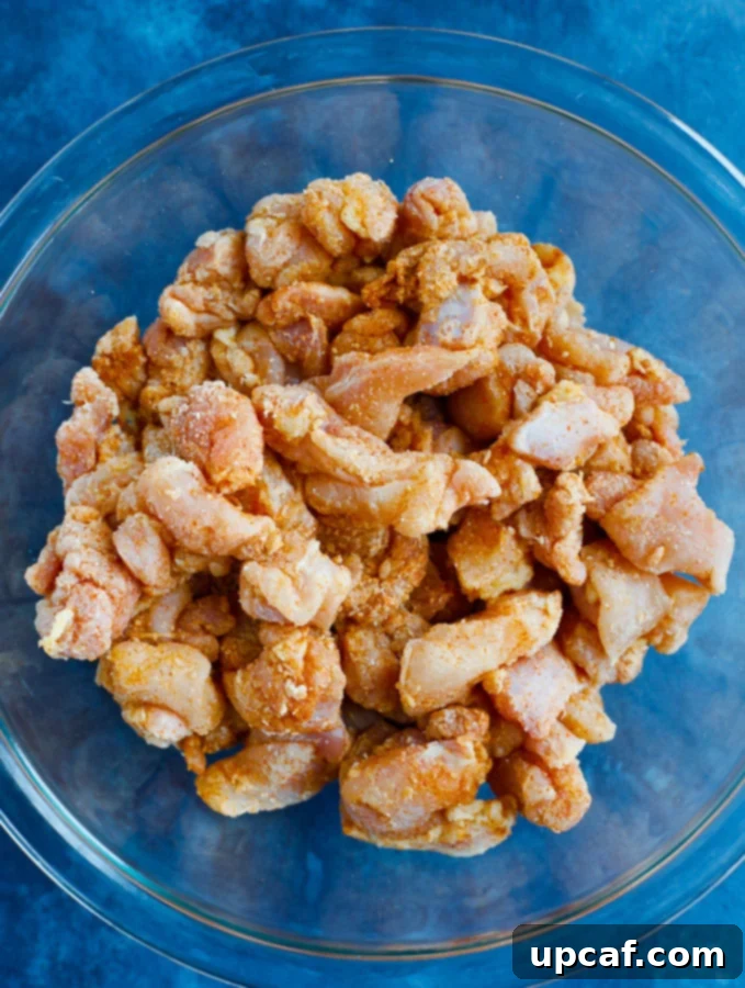 small cubed chicken in a glass bowl after being mixed with the flour and spices.