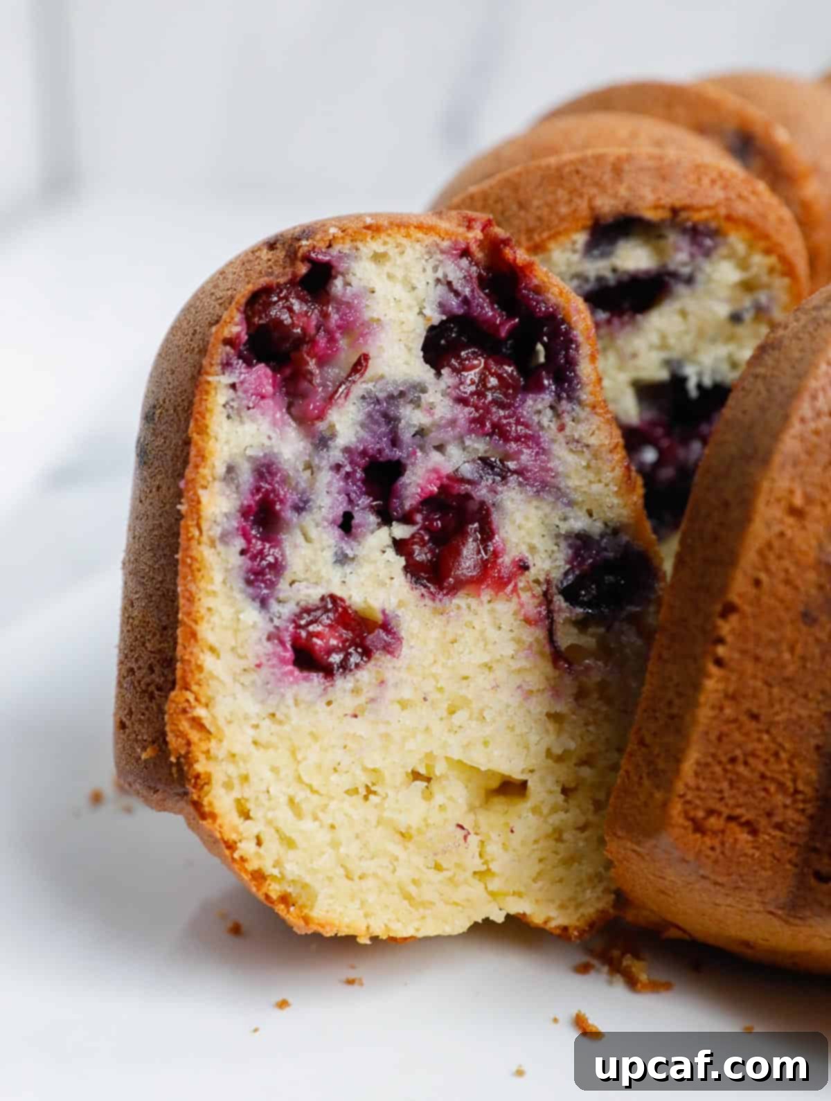 A beautiful slice of moist blueberry Bundt cake, revealing a tender crumb studded with juicy blueberries.
