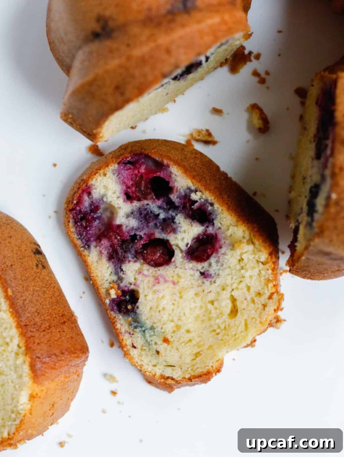 A slice of blueberry Bundt cake presented next to the full Bundt cake, ready for serving.