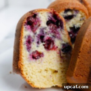 A slice of moist blueberry Bundt cake, revealing a tender crumb studded with juicy blueberries.