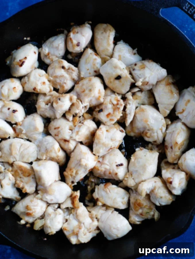 THAI RED CURRY CHICKEN: A CLASSIC RECIPE WITH COCONUT MILK AND VEGETABLES 2 Sautéed chicken pieces cooking in a skillet, preparing for the curry