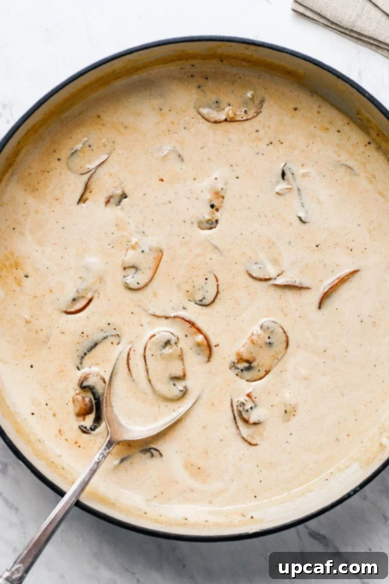 Sliced mushrooms and minced garlic sautéing in butter in a hot skillet, ready for the creamy sauce.