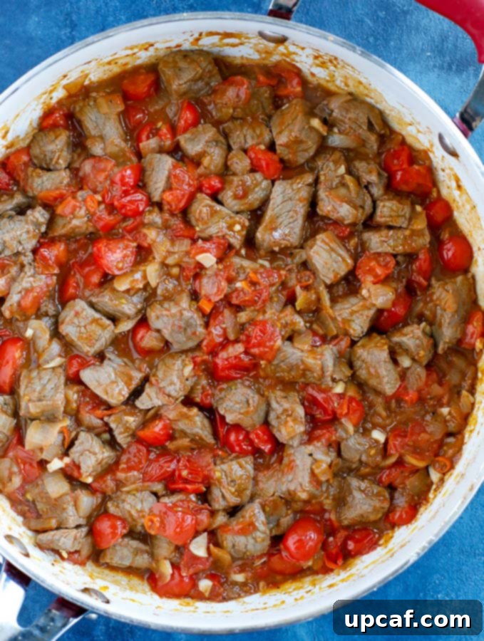 Adding tomatoes and garlic to beef stew