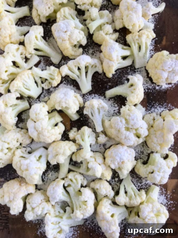 Cauliflower dusted with corn flour on a baking sheet.