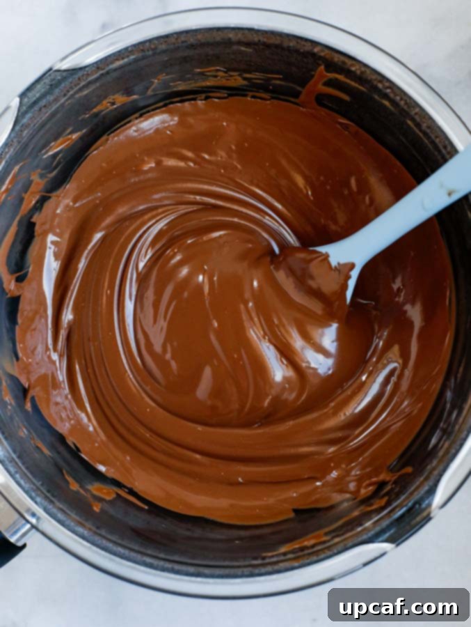 Lustrous, melted chocolate shown in a pristine pot, highlighting its rich, smooth texture.