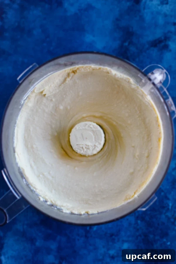 Lebanese Hummus with Savory Spiced Meat 3 A food processor with fresh hummus on a blue counter.