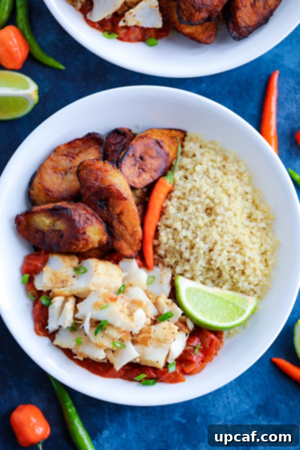 Caribbean Jerk Power Bowl 4 A white bowl with Caribbean Jerk Fish, quinoa, tomato sauce, and fried plantains topped with chilies on a blue counter.