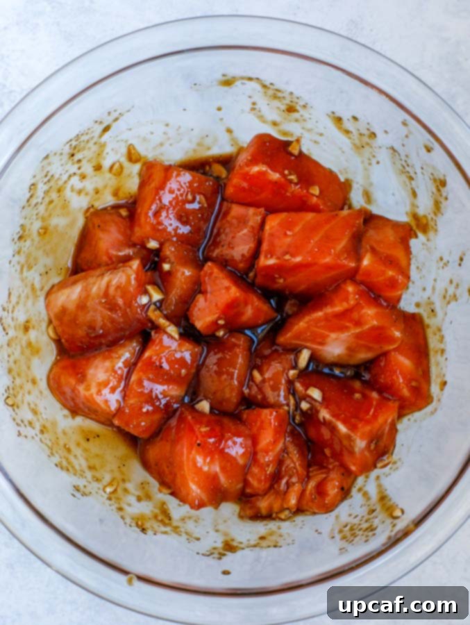Glazed Teriyaki Salmon Medley 3 Salmon cubes marinating in a glass bowl of teriyaki sauce.
