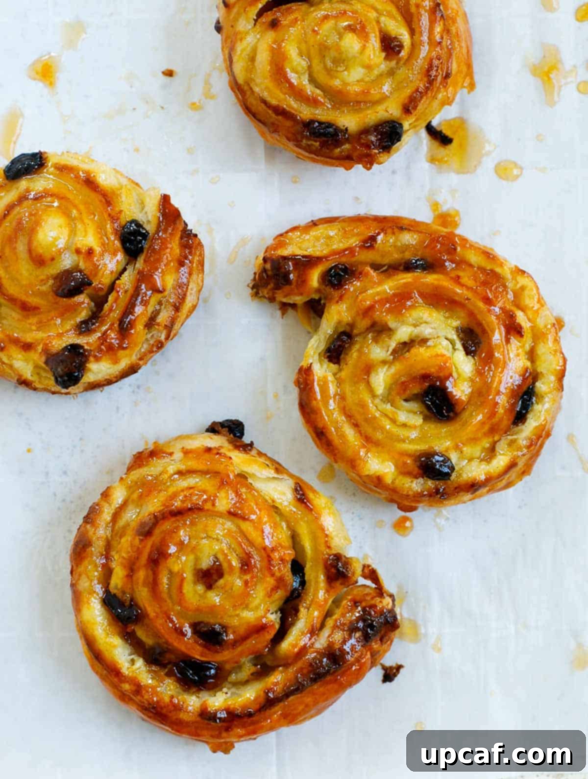 Effortless Pain Aux Raisins 13 baked pain aux raisins on a sheet pan.
