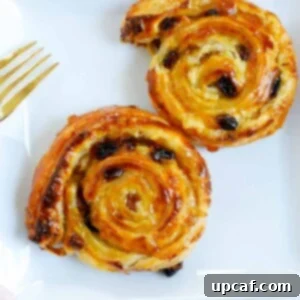 Effortless Pain Aux Raisins 15 two baked pain aux raisins on a white plate.