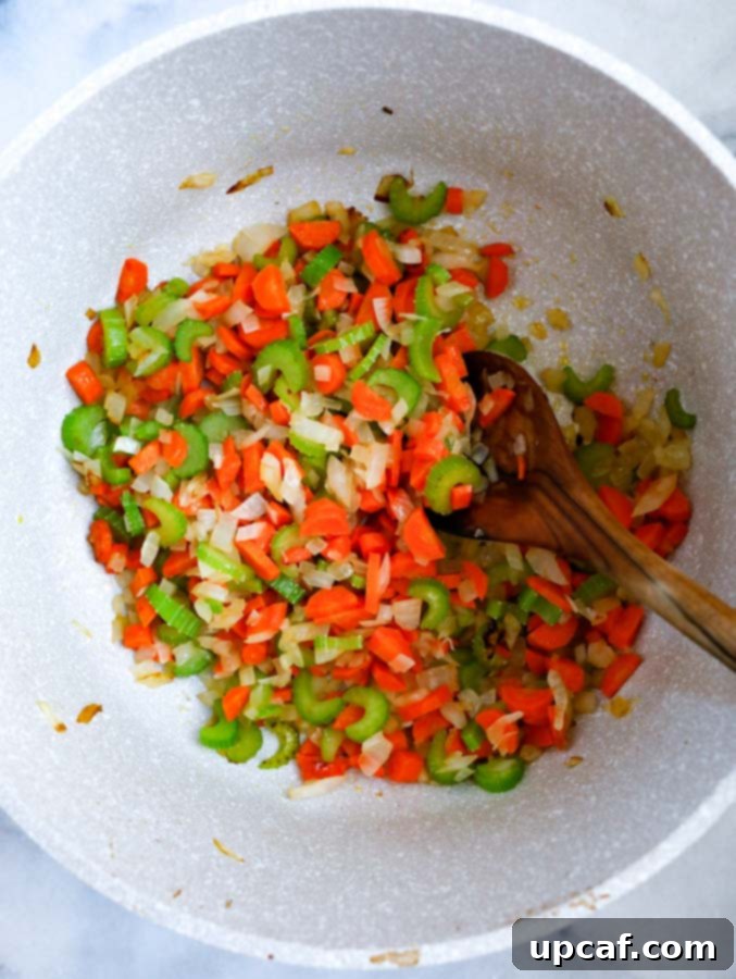 Bright Lemon Chicken Orzo Soup 3 Diced onions, carrots, and celery sautéing in a pot for soup.