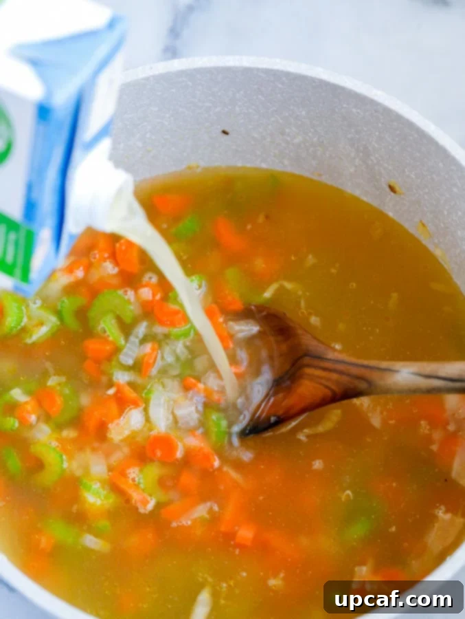 Bright Lemon Chicken Orzo Soup 4 Top down shot of chicken broth being added to a pot of sautéed vegetables.