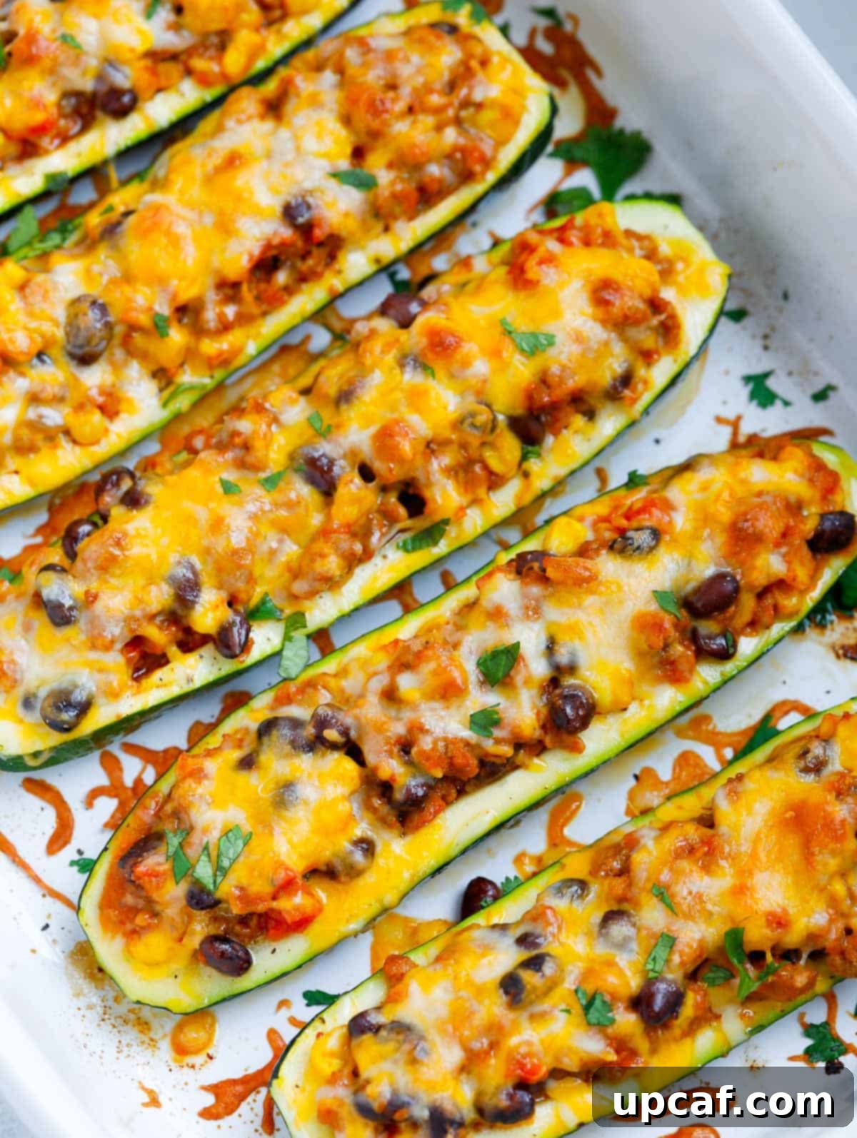 Loaded Zucchini Boats 2 Freshly baked zucchini boats in a rustic baking dish, garnished with herbs.