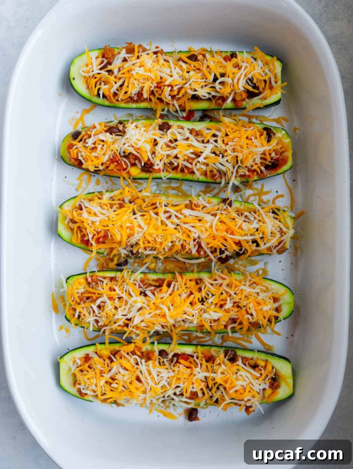 Loaded Zucchini Boats 5 Zucchini boats generously topped with shredded cheese, ready for the final bake.