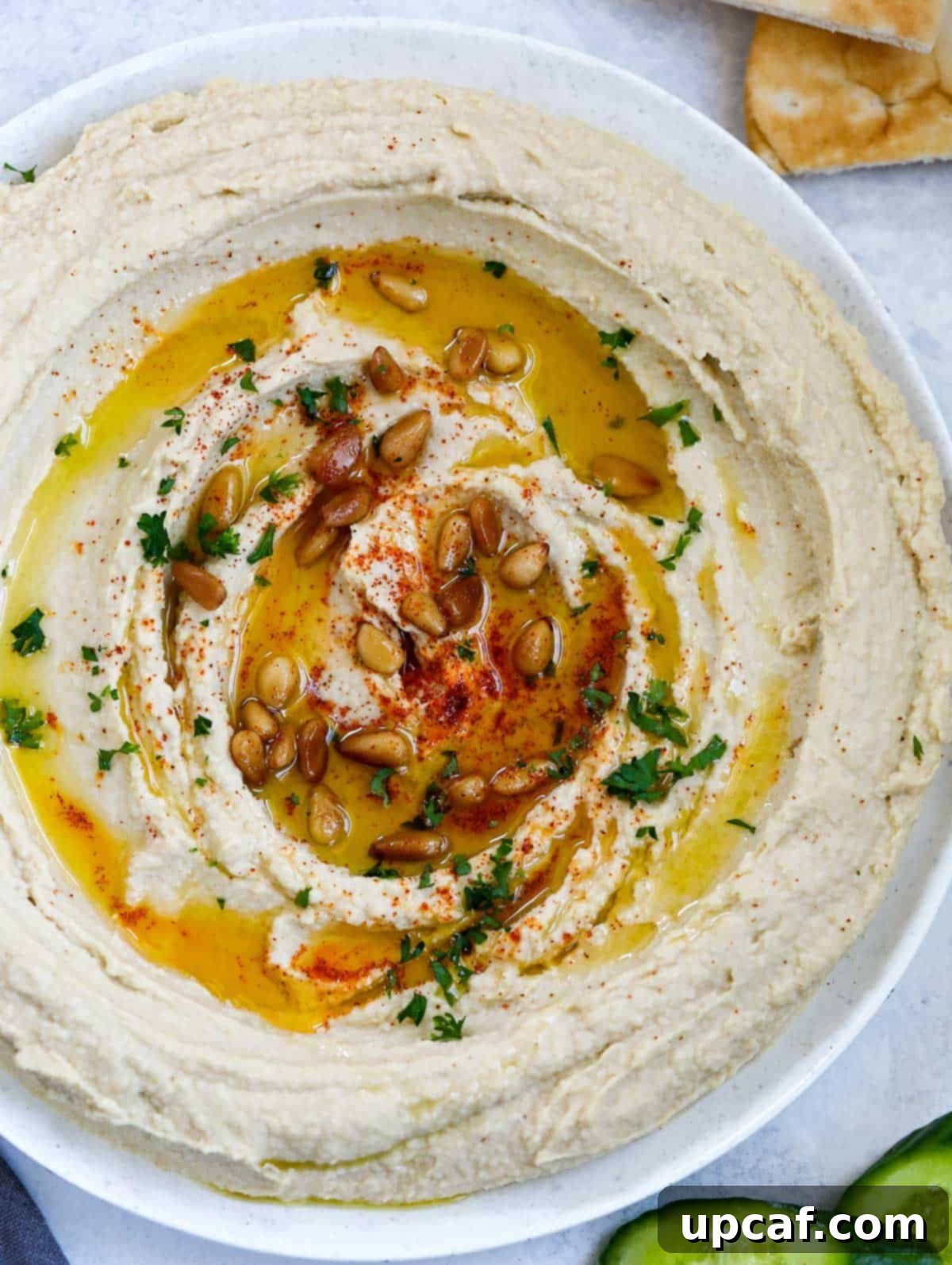 Effortlessly Delicious Lebanese Hummus 2 lebanese hummus in a plate, topped with olive oil, paprika, pine nuts