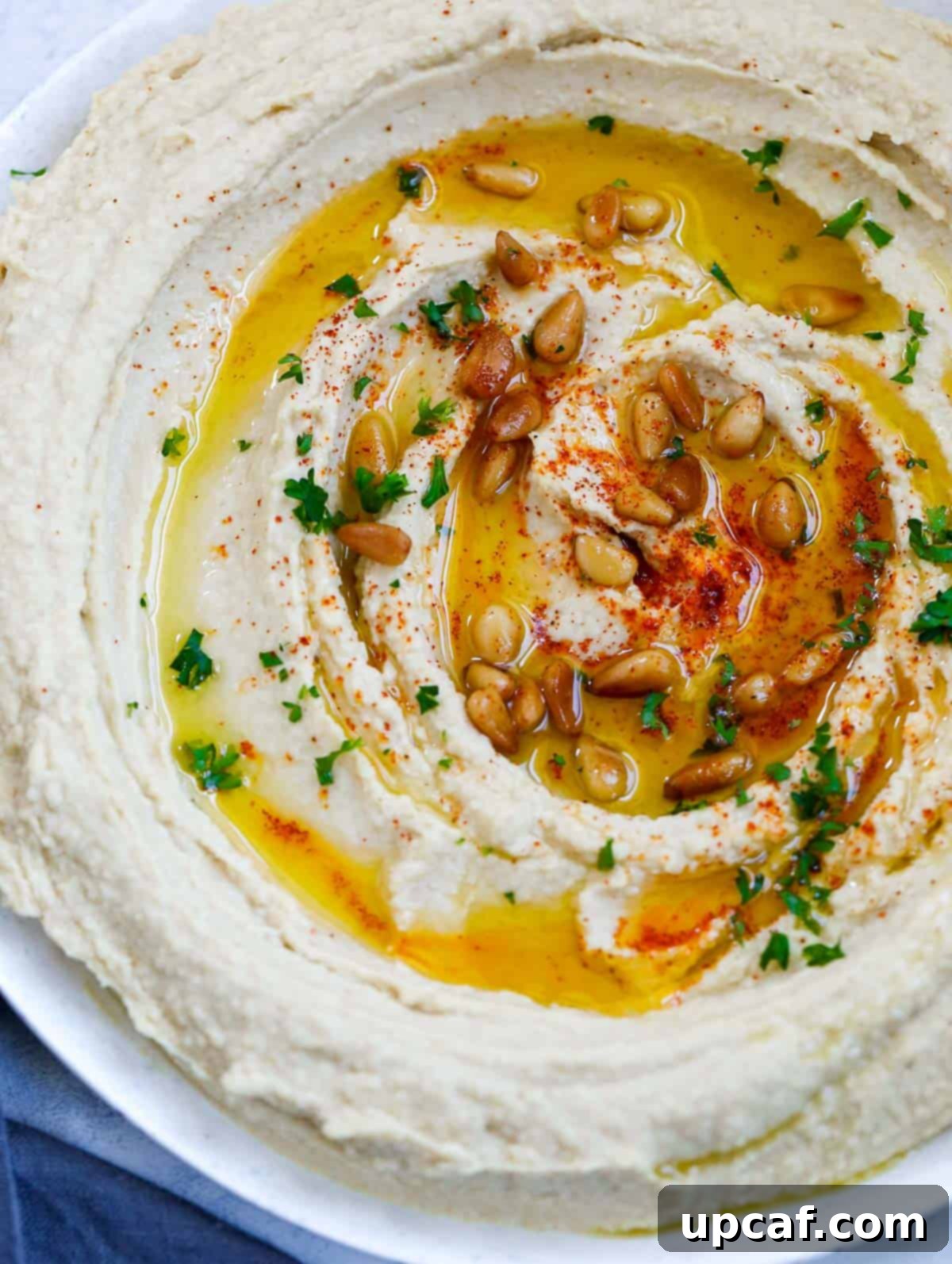 Effortlessly Delicious Lebanese Hummus 8 lebanese hummus in a plate, topped with olive oil, paprika, pine nuts
