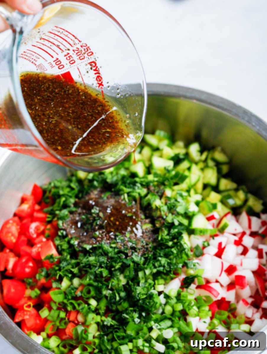 Crisp Cabbage Fattoush 7 A stream of tangy, red dressing being poured over the colorful Cabbage Fattoush Salad in a bowl.