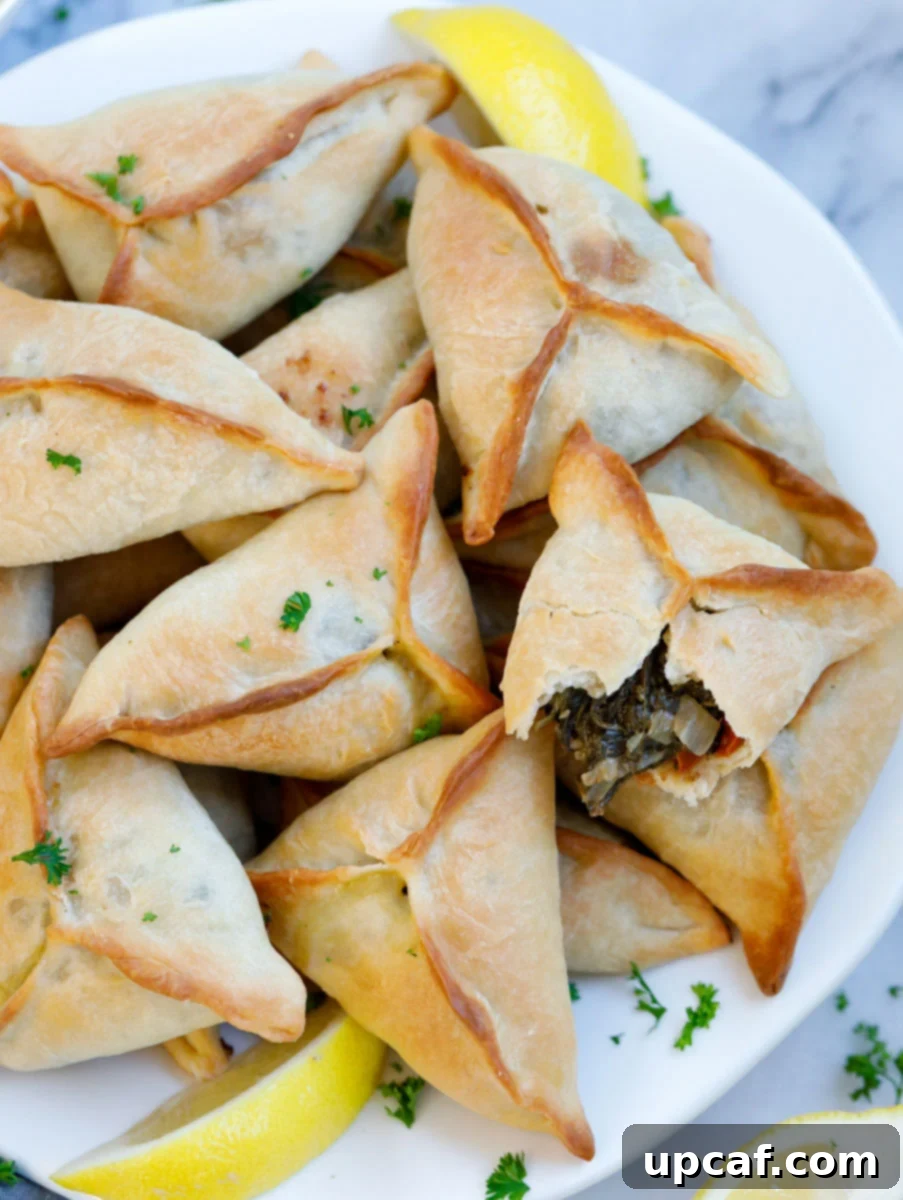 baked Lebanese fatayer spinach pies served on a plate with lemon wedges