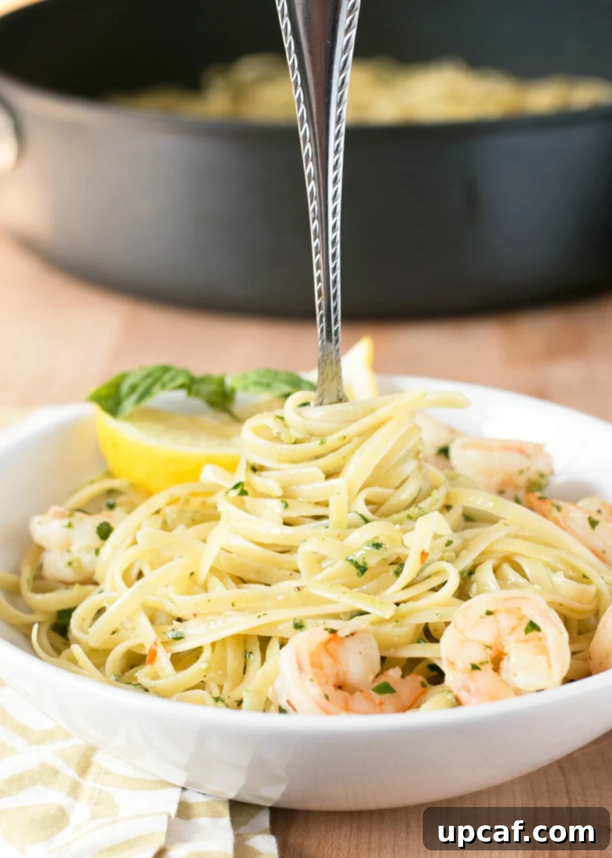 Large white bowl of pesto shrimp scampi pasta with a fork in the center