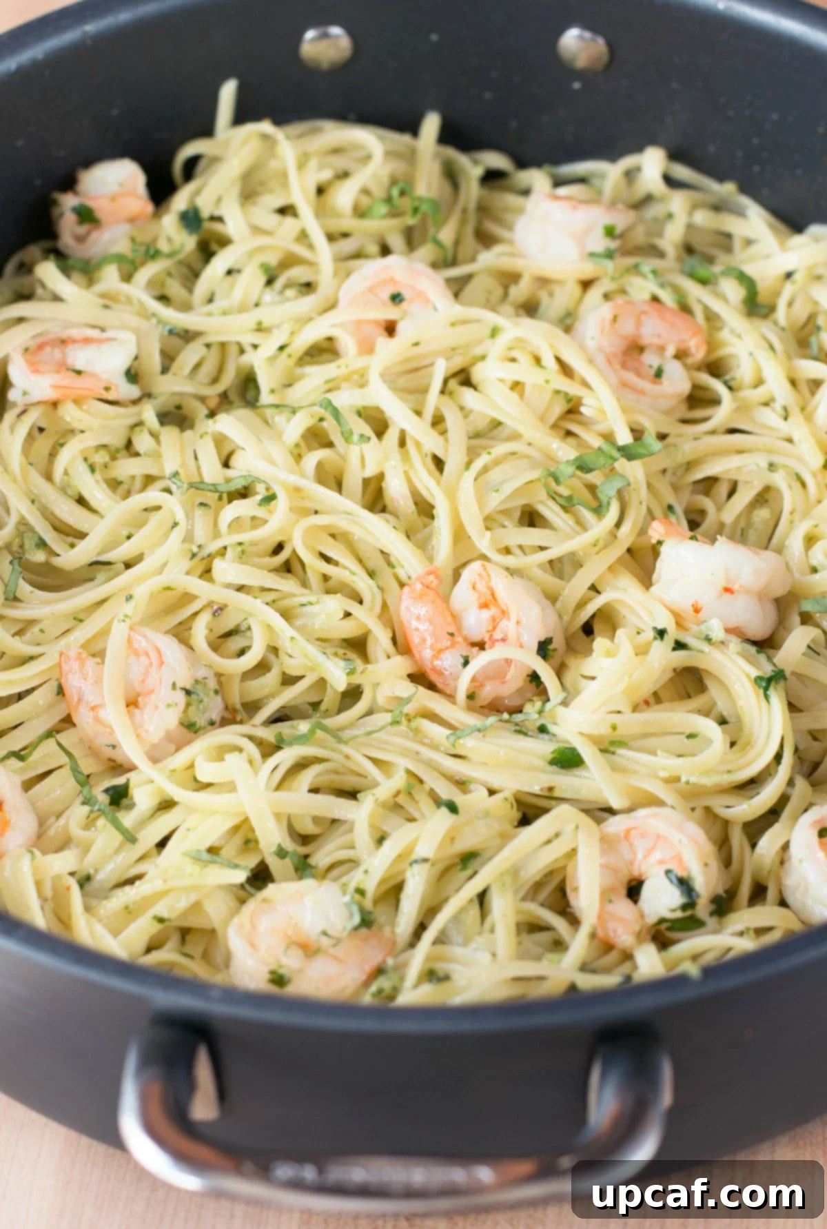 Pesto shrimp scampi with pasta being tossed together in a large stockpot