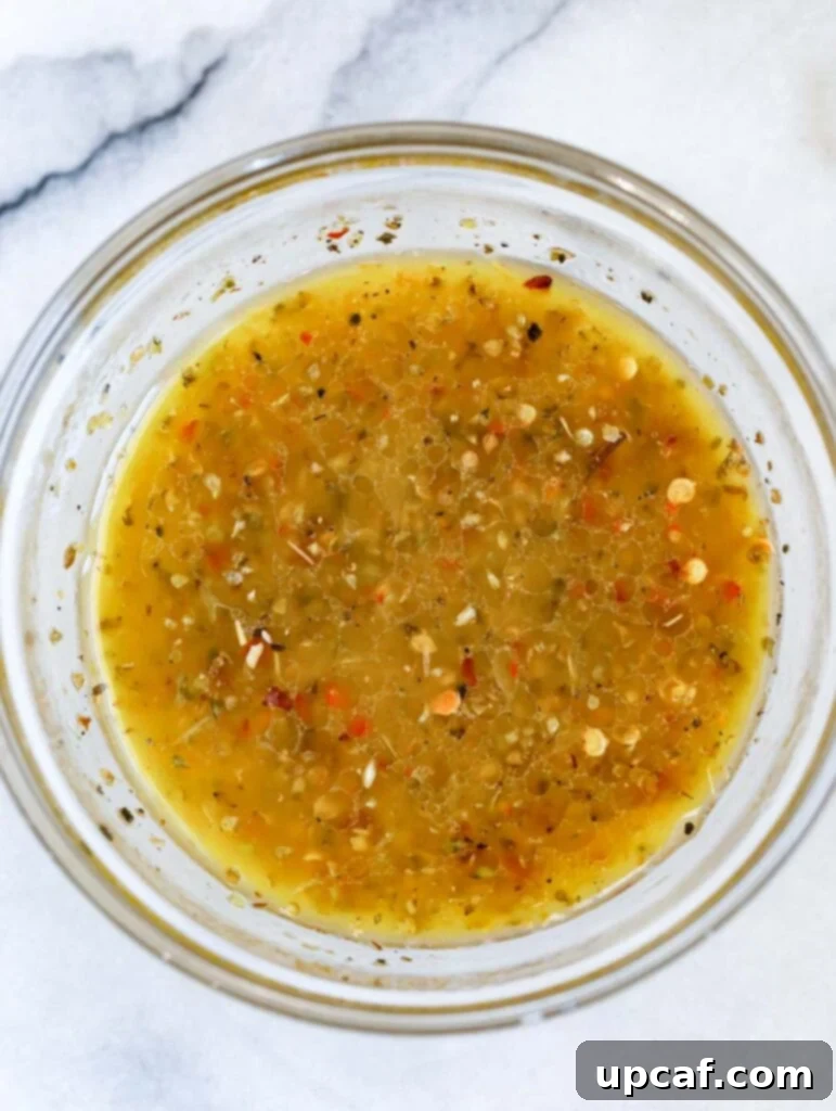 A small bowl of homemade Mediterranean dressing, showing a creamy, light yellow consistency with specks of herbs and spices.