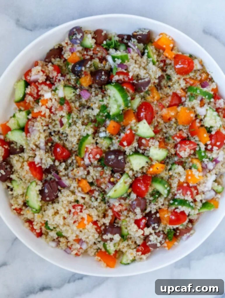 Top-down view of the Mediterranean quinoa salad after being dressed, showcasing the glistening vegetables and quinoa coated in the zesty dressing.