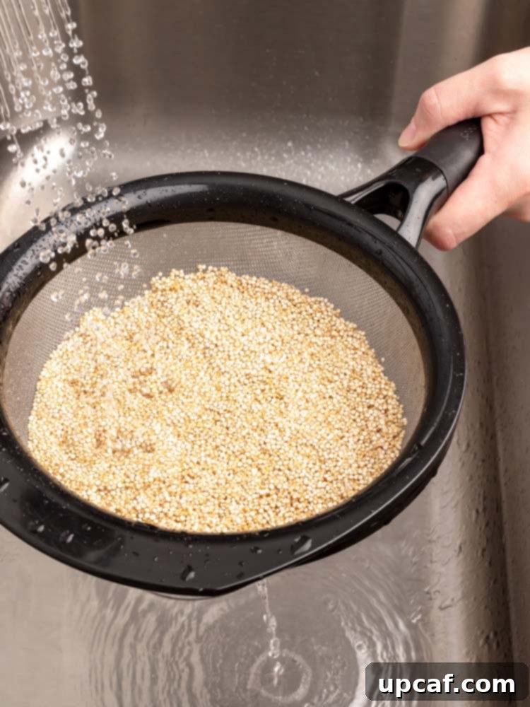 Quinoa being rinsed in a fine-mesh strainer under running water.