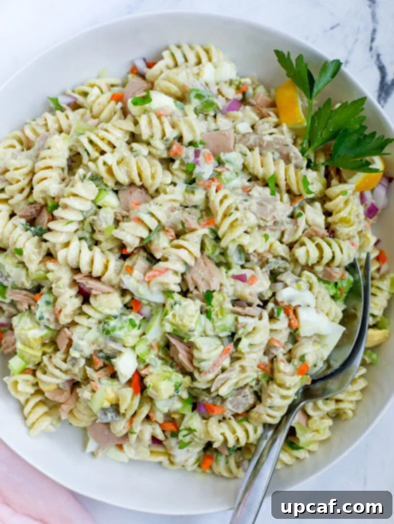 The Ultimate Tuna Pasta Salad 7 Tuna Pasta Salad Recipe in a bowl with a fork and spoon