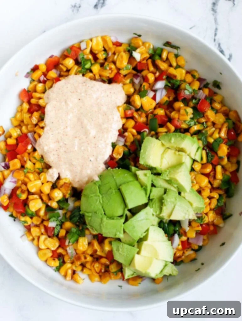 Street Corn Salad in a bowl with visible avocado and dressing, ready to be served.
