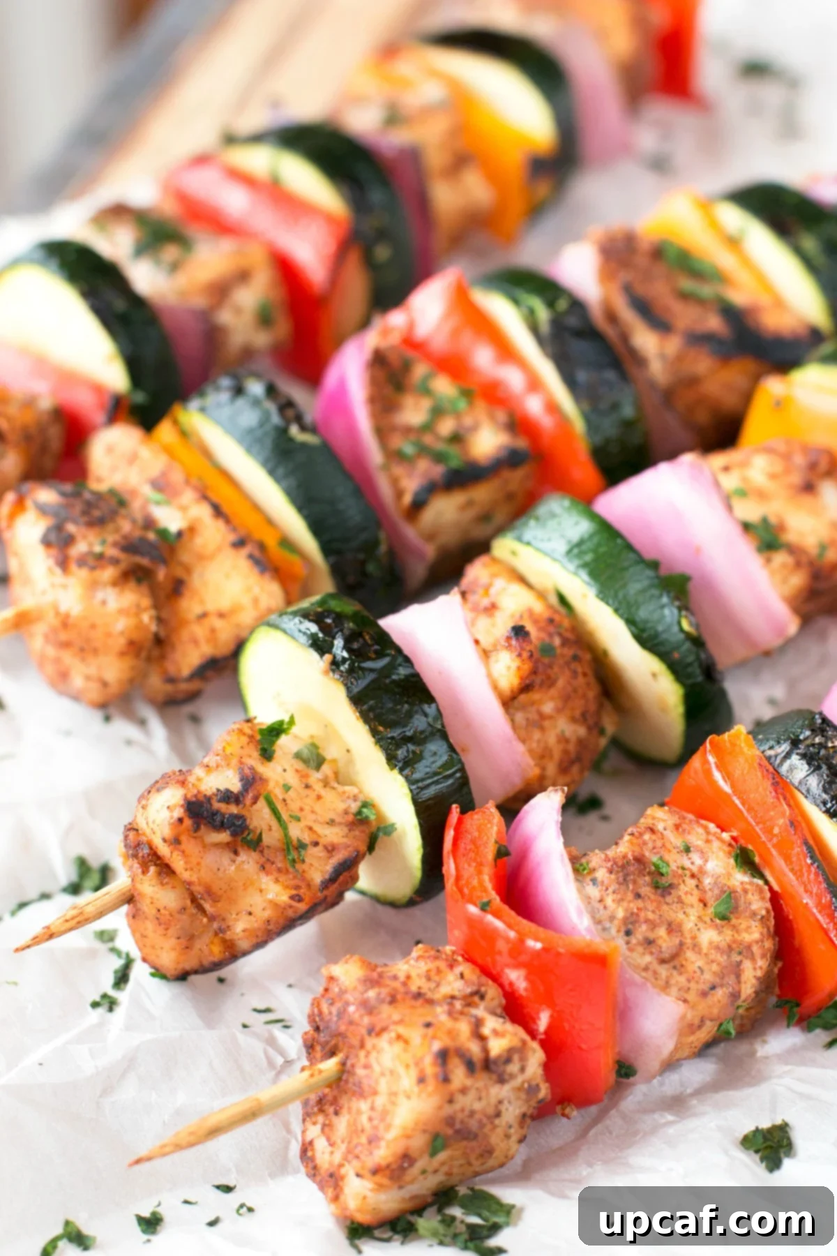 Fiery Chili Chicken Skewers with Rainbow Peppers 3 Chicken skewers with zucchini pepper and onion on a baking sheet