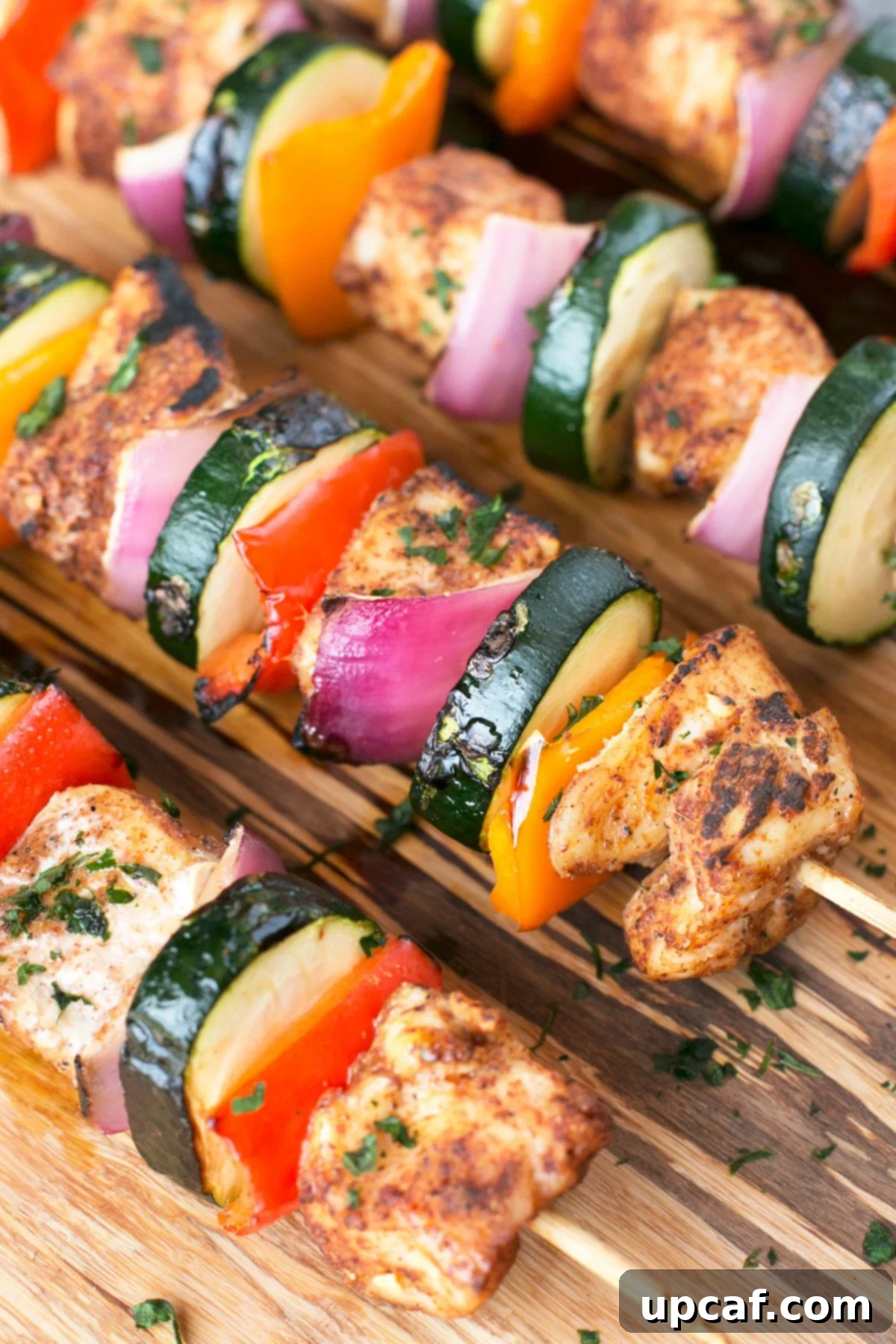 Fiery Chili Chicken Skewers with Rainbow Peppers 4 Seasoned vegetable and chicken kabobs on a wooden platter