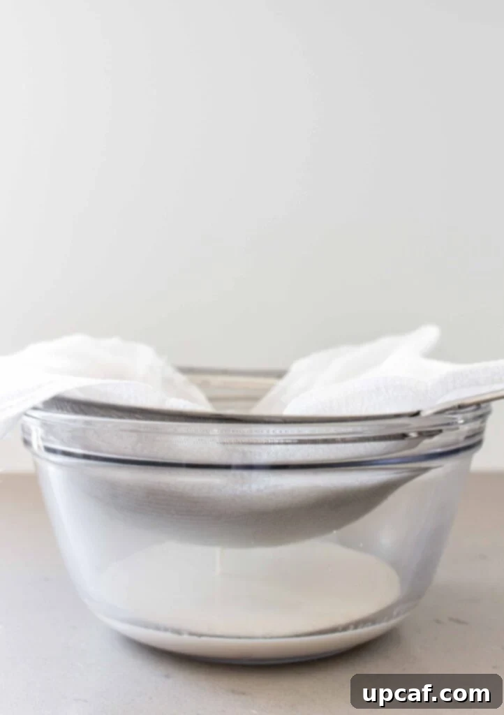 Fresh Almond Milk From Scratch 8 straining almond milk in a strainer and cheesecloth