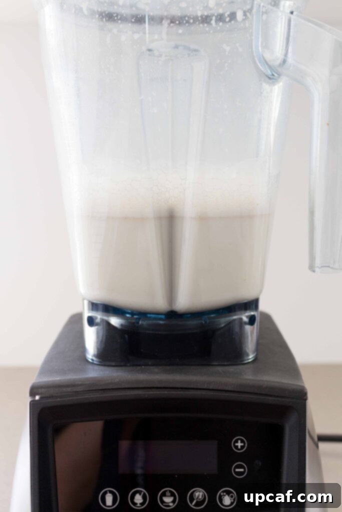 Oat milk blending smoothly in a high-speed blender, creating a creamy white liquid.