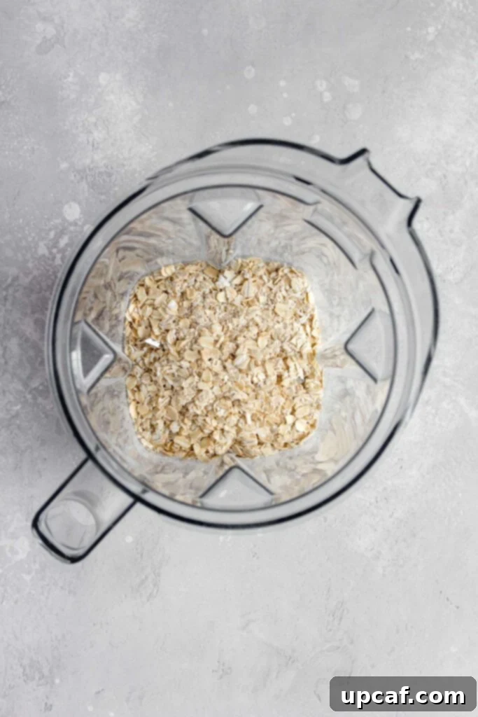 Whole oats being poured into a blender.