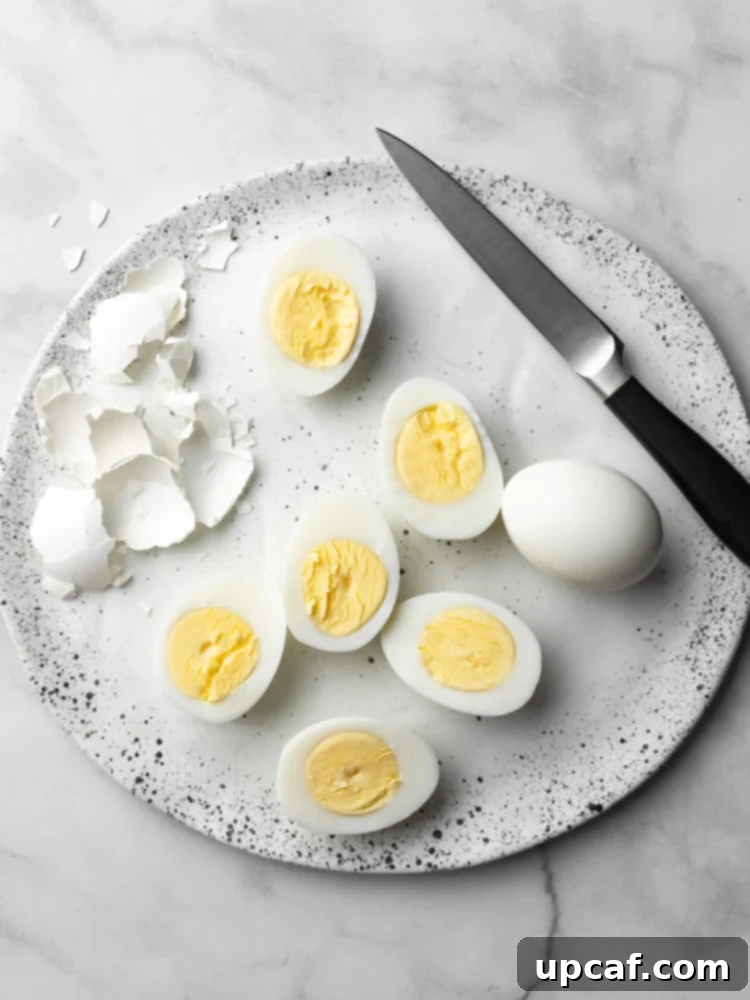 Peeled hard-boiled eggs on a plate, with some sliced to reveal their perfect, creamy yolks.