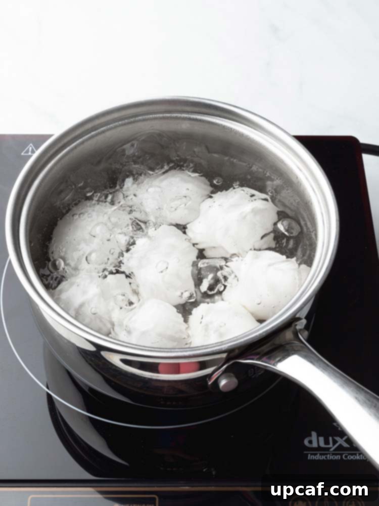 Eggs being gently lowered into a pot of simmering water using a slotted spoon.